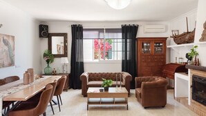 A living room with a dining table, sofas, a fireplace, and a large window with curtains. - Holiday Home 'Susana' with Private Pool, Private Terrace and Wi-Fi (Santa Eulària des Riu)