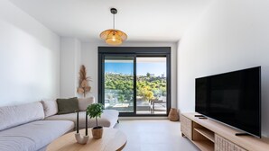 A modern living room with a sofa, a coffee table, a TV, and a balcony with a city view. - Apartment 'Middle Views West' with Sea View, Wi-Fi and Air Conditioning (Fuengirola)