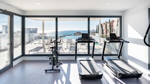A modern gym with exercise equipment and large windows overlooking a rooftop area. - Apartment 'Middle Views West' with Sea View, Wi-Fi and Air Conditioning (Fuengirola)