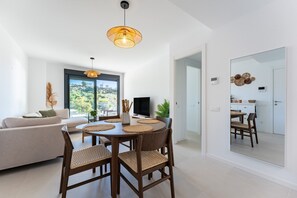Un salon moderne comprenant un canapé, une table à manger, des chaises, un téléviseur et un grand miroir.