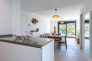 A modern kitchen with a central island, a dining area with a table and chairs, and a large sliding glass door leading to an outdoor area. - Apartment 'Middle Views West' with Sea View, Wi-Fi and Air Conditioning (Fuengirola)