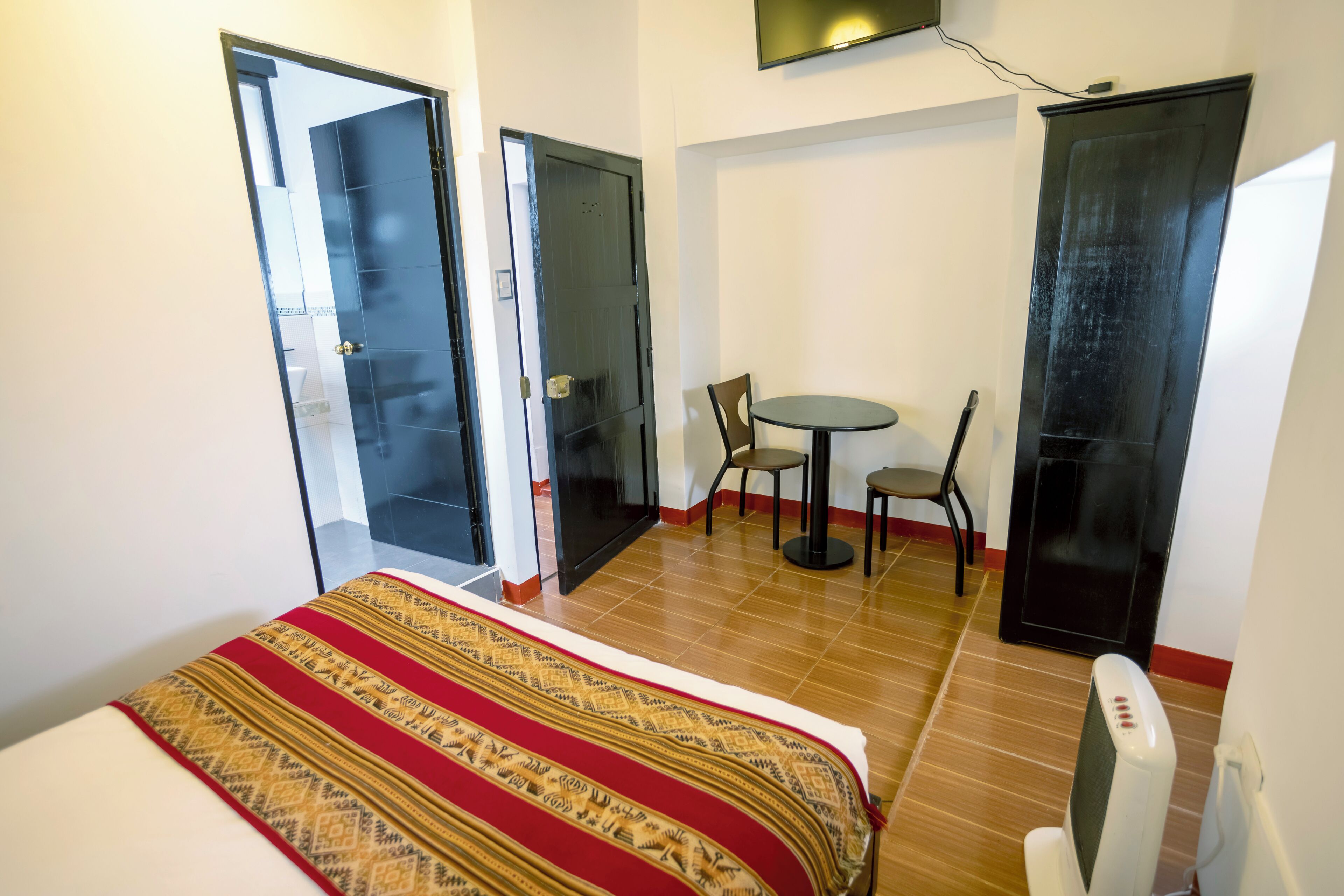 A hotel room with a bed, a small table with chairs, and a TV.
