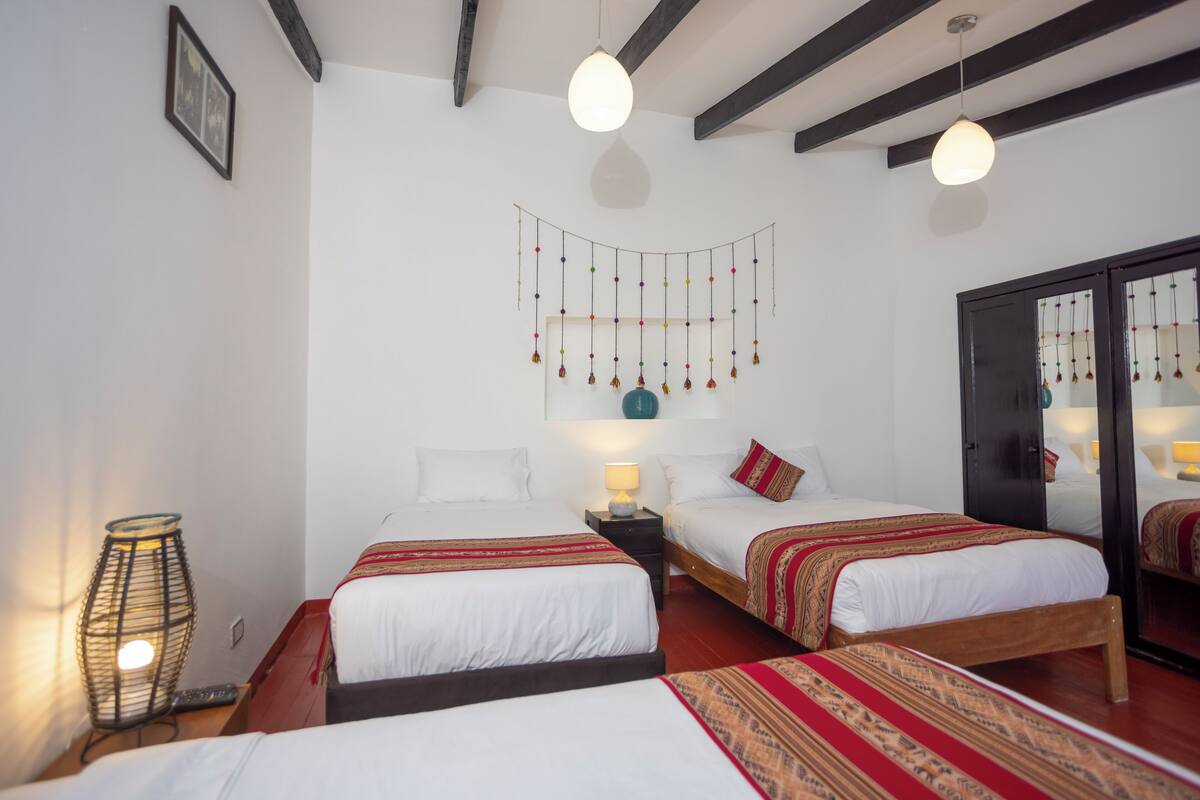 Une chambre d’hôtel avec deux lits, un élément décoratif suspendu, une lampe et une armoire.