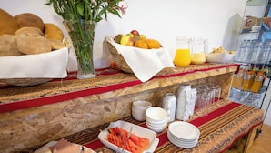 A breakfast buffet with bread, fruits, and beverages. - KUSKA SAN BLAS (Cusco)