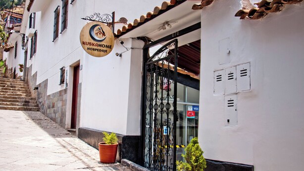 A building with a sign reading "KUSKAHOME HOSPEDAGJE" and a black wrought iron gate. - KUSKA SAN BLAS (Cusco)