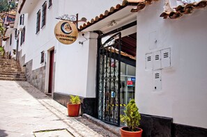 A building with a sign reading "KUSKAHOME HOSPEDAGJE" and a black wrought iron gate.