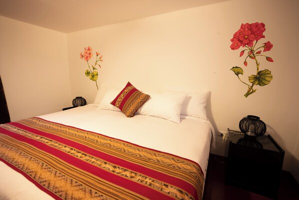 A neatly made bed with a patterned blanket, a pillow, and a bedside table with a lamp.