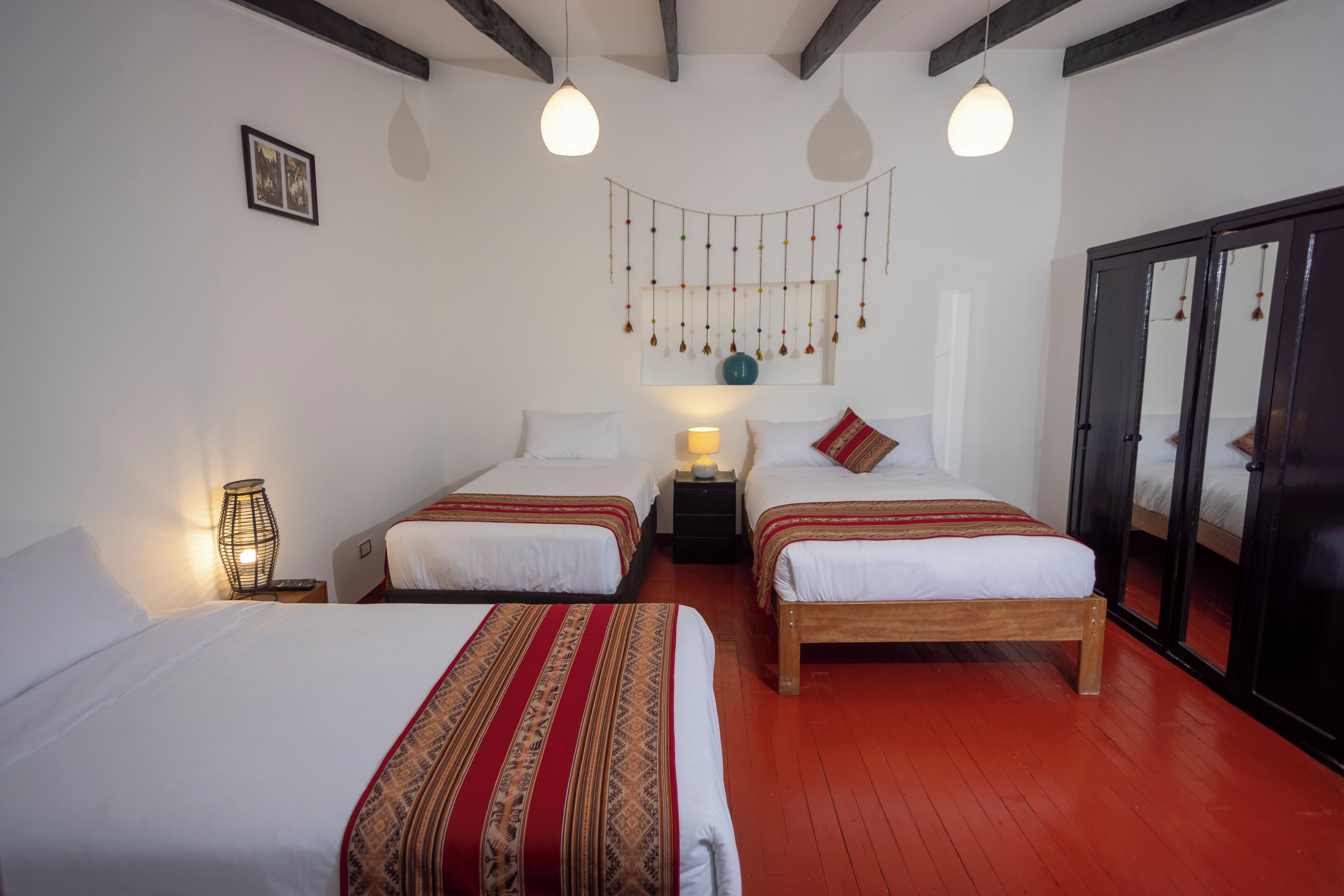 A hotel room with two single beds, a wardrobe, a hanging decoration, and a lamp.