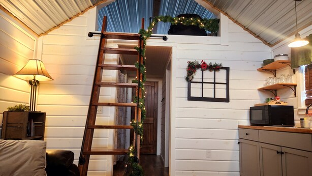 A cozy interior with a wooden ladder, a small kitchen area, and a living space with a couch. - Cabin of Western Skies:  loft, Wi-Fi , and tiny home living-close to OSU (Perkins)