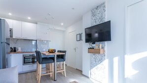 A modern kitchen with white cabinets, a built-in oven, and a dining area with a table and chairs. - Apartment 'St Raphael' with Balcony and Wi-Fi (Saint-Raphaël)