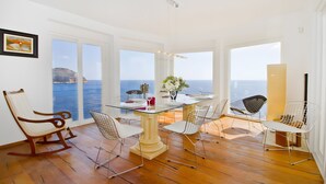 A dining area with a glass table, white chairs, and a view of the sea. - Villa 'Blanca' with Sea View, Wi-Fi and Air Conditioning (Capdepera)