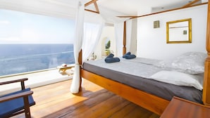 A bedroom with a wooden four-poster bed, a view of the ocean, and a small table with a chair. - Villa 'Blanca' with Sea View, Wi-Fi and Air Conditioning (Capdepera)
