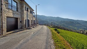 Une construction en pierre dotée d’un garage, d’un balcon et offrant une vue sur des collines ondulantes.