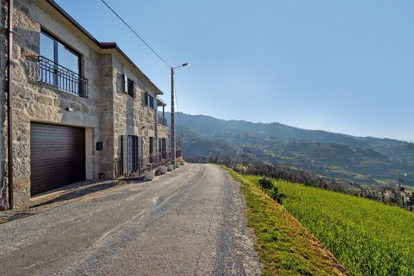 A stone building with a garage, a balcony, and a view of rolling hills.