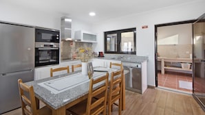 Une cuisine moderne avec une table à manger, des chaises et un réfrigérateur.