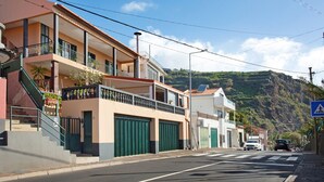 Calle residencial con casas, un paso de peatones y un paisaje montañoso al fondo.