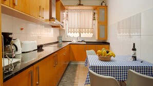 Una cocina con armarios de madera, una mesa de comedor con mantel a cuadros y un frutero.