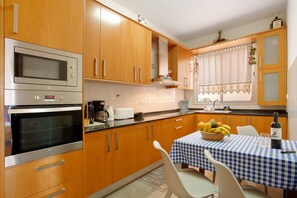 A kitchen with wooden cabinets, a microwave, and a table with a checkered tablecloth.