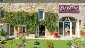 Un bâtiment en pierre avec une enseigne indiquant qu’il s’agit d’une pizzeria, une petite fenêtre et une porte.