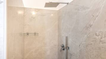 A modern shower with a glass door, a handheld showerhead, and a wall-mounted control panel.