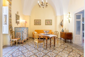 A dining area with a table, chairs, a chandelier, and a patterned floor. - Apartment 'Donna Cesarina - Maison De Charme' with Private Terrace, Wi-Fi and Air Conditioning (Maruggio)
