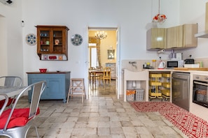 A kitchen with a dining area, a blue cabinet, and a red patterned rug. - Apartment 'Donna Cesarina - Maison De Charme' with Private Terrace, Wi-Fi and Air Conditioning (Maruggio)