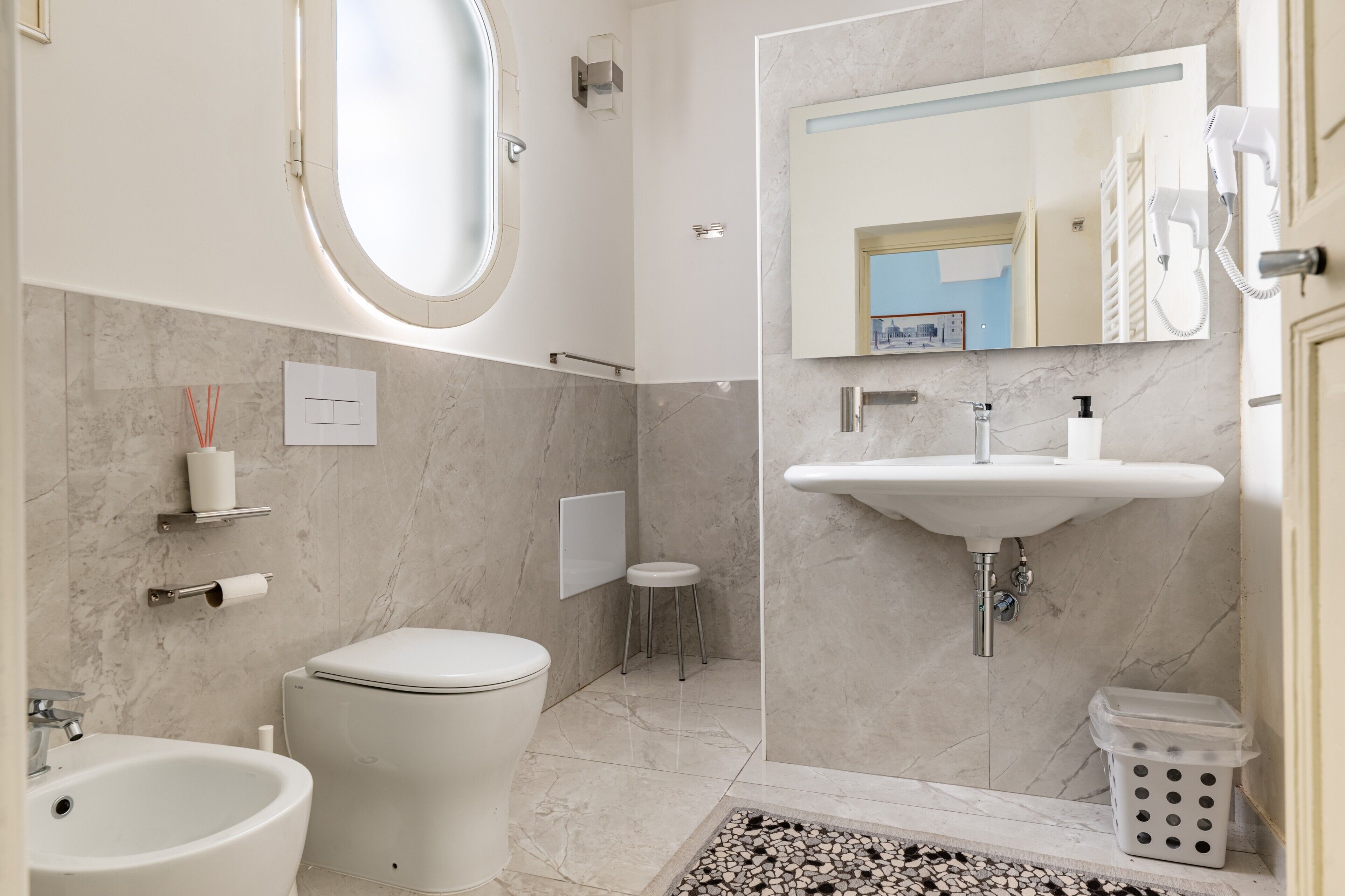 Une salle de bain moderne équipée de toilettes, d’un bidet, d’un lavabo et d’un miroir.