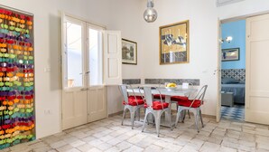 Un comedor con una mesa y sillas, una lámpara colgante y una puerta con decoración colorida.