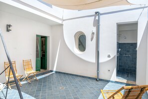 A sunlit room with a tiled floor, a green door, a circular window, and a shower area. - Apartment 'Donna Cesarina - Maison De Charme' with Private Terrace, Wi-Fi and Air Conditioning (Maruggio)