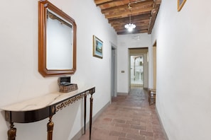 A hallway with a marble console table, a wooden-framed mirror, and a tiled floor.