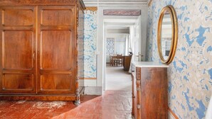 A room with a large wooden wardrobe, a mirror, and patterned wallpaper. - Apartment 'Il Conte' with Shared Pool and Shared Garden (Massarosa)