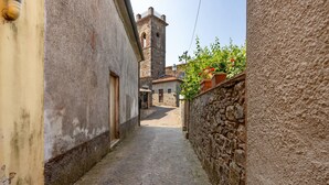 A narrow cobblestone alley with stone walls, a tower, and a building with a door. - Apartment 'La Castellana' with Shared Pool, Wi-Fi and Air Conditioning (Massarosa)