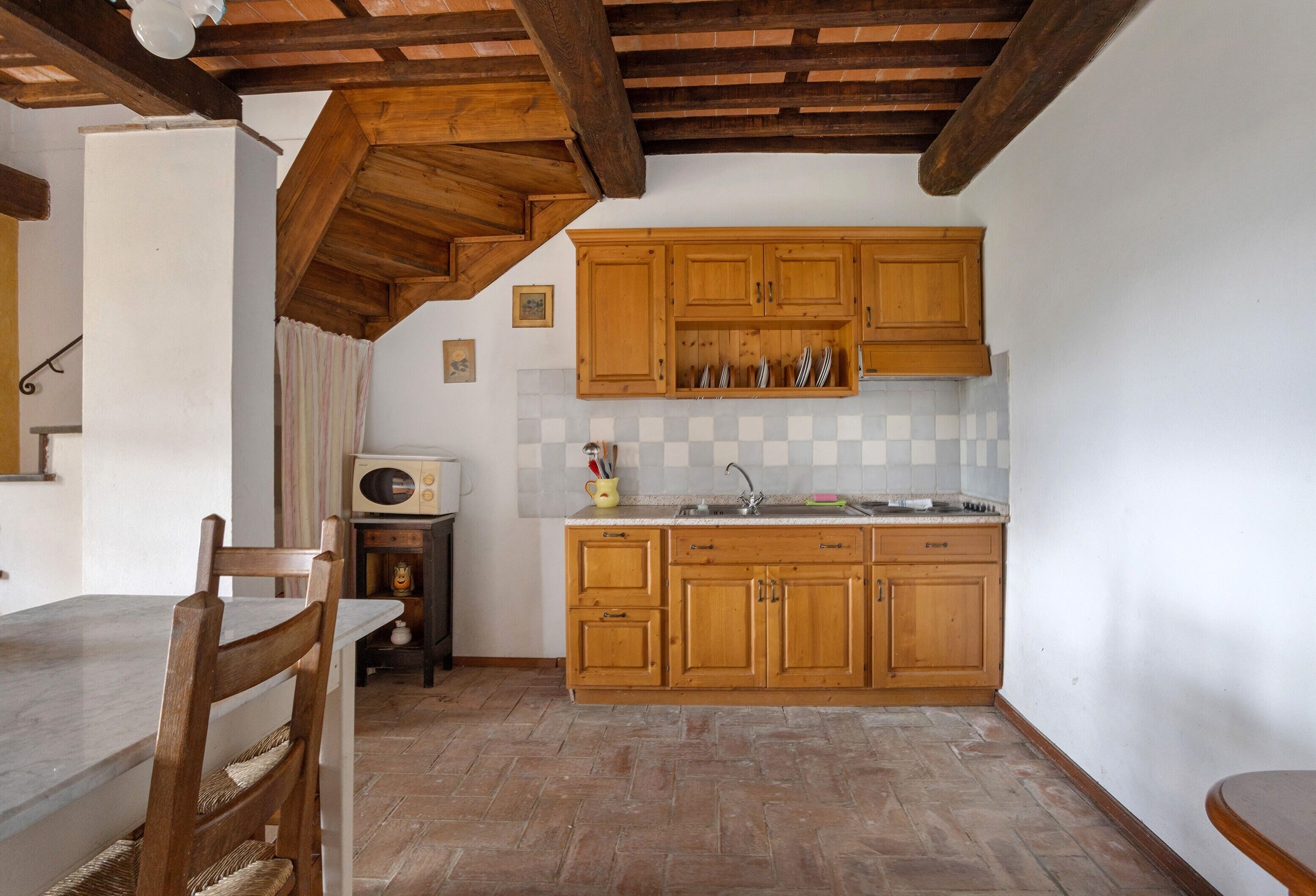 Eine Küche mit Holzausbau, gefliestem Fliesenspiegel und Steinböden.
