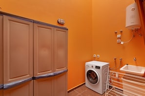 A laundry room with a washing machine, a sink, and a water heater.