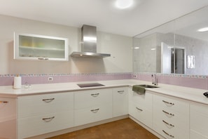 A kitchen with white cabinets, a stainless steel range hood, a built-in microwave, and a tiled backsplash.