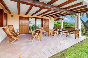 Une terrasse extérieure avec des meubles en bois, une pergola et une vue sur la campagne.