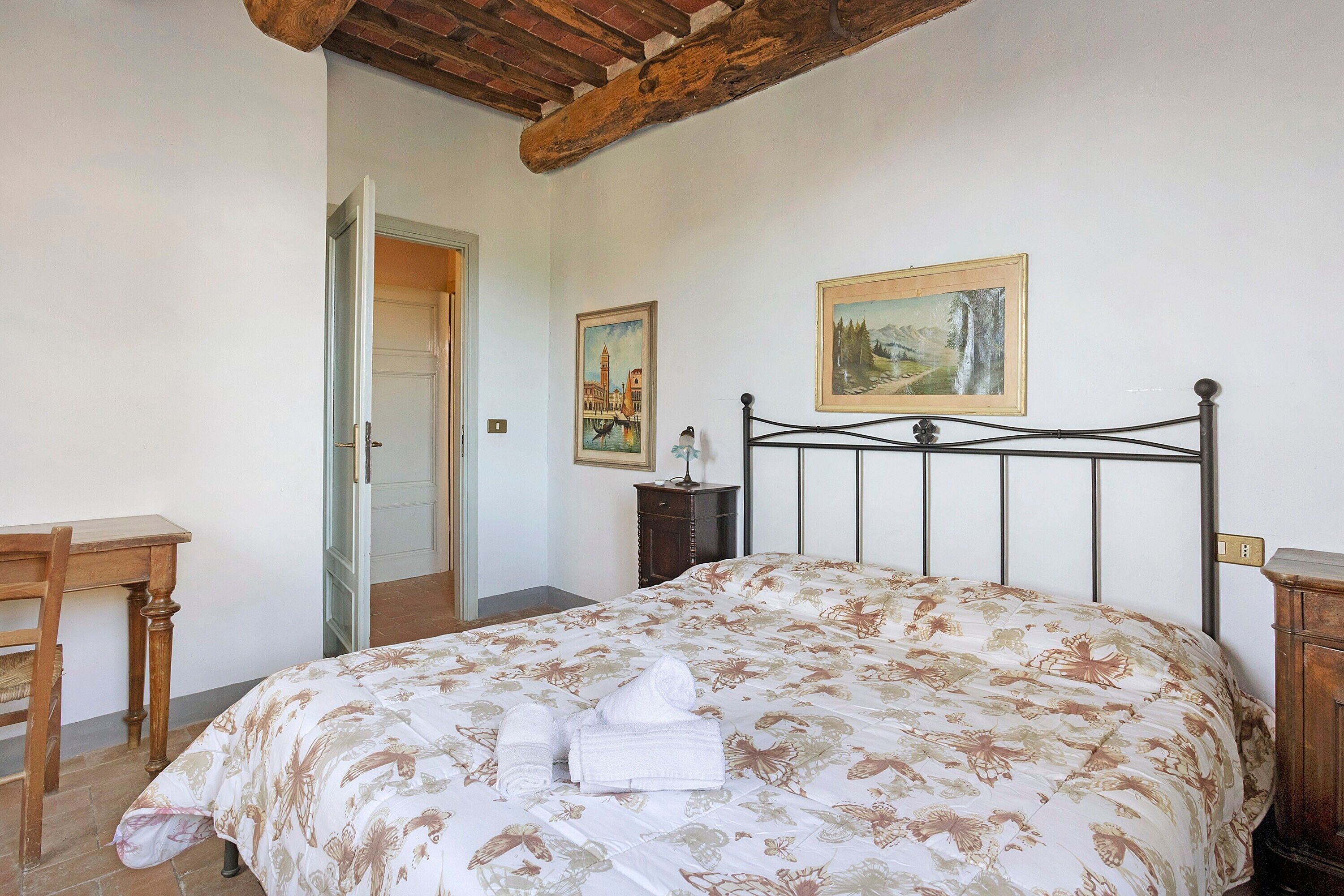 Un dormitorio con una cama, una silla de madera, un escritorio y una puerta.