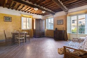 Quarto com teto de madeira, chão de azulejos, uma cama, uma mesa com cadeiras e um armário.