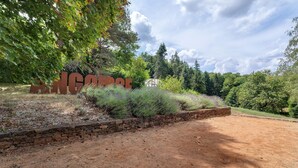 A dirt path leading to a stone wall with a large sign.