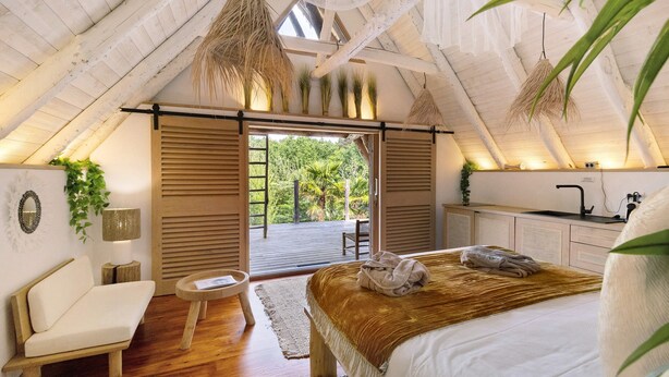 A bedroom with a bed, a chair, a desk, and a view of greenery outside.