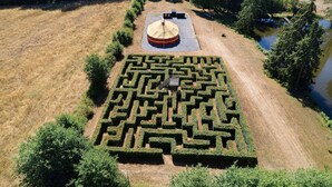 Een doolhofachtige tuin met een centrale ronde constructie en een klein vijvertje.