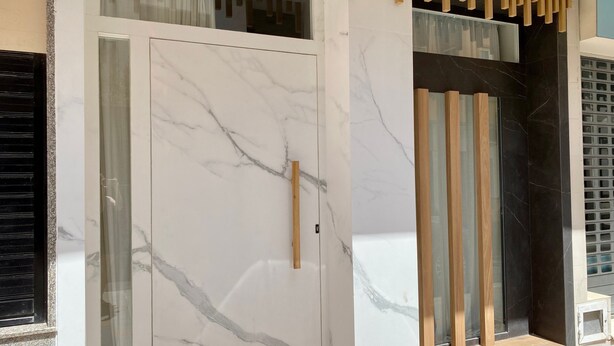 Une entrée moderne avec une porte en marbre, des panneaux en bois et une fenêtre en verre.