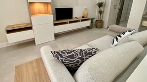 Un salon moderne avec un canapé, un téléviseur et des rangements intégrés.