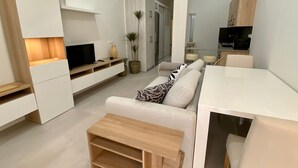 Un salon moderne comprenant un canapé, une table basse, un téléviseur et un coin repas avec une table et des chaises.