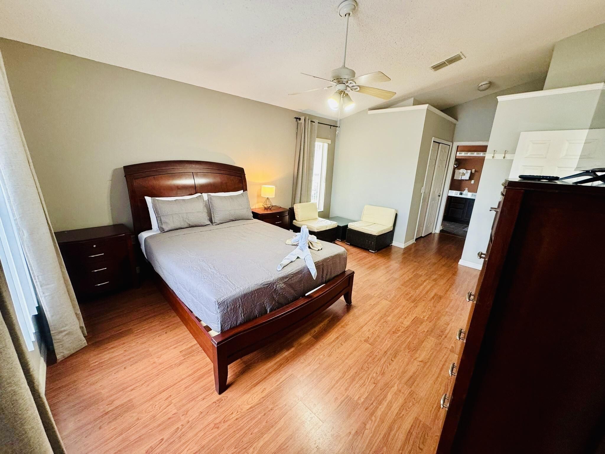 Een hotelkamer met een houten bed, een plafondventilator, een bureau en een kledingkast.