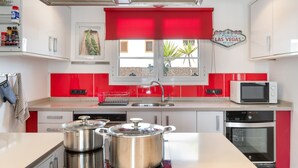 Una cocina moderna con detalles en rojo, microondas, horno y ventana con vistas.