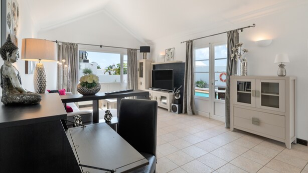 Una sala de estar moderna con comedor, televisión y vistas al exterior.