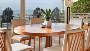 A round wooden table with six chairs, a potted plant, and a lamp on a balcony overlooking the ocean. - Cliffside Oceanfront Gem - Stunning Views & Yard (Encinitas)