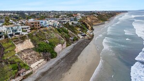 A coastal residential area with houses along the beach, a rocky shoreline, and a clear sky. - Cliffside Oceanfront Gem - Stunning Views & Yard (Encinitas)