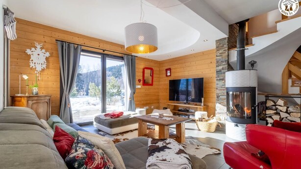 Una sala de estar acogedora con chimenea, televisor y un amplio ventanal con vistas al exterior.
